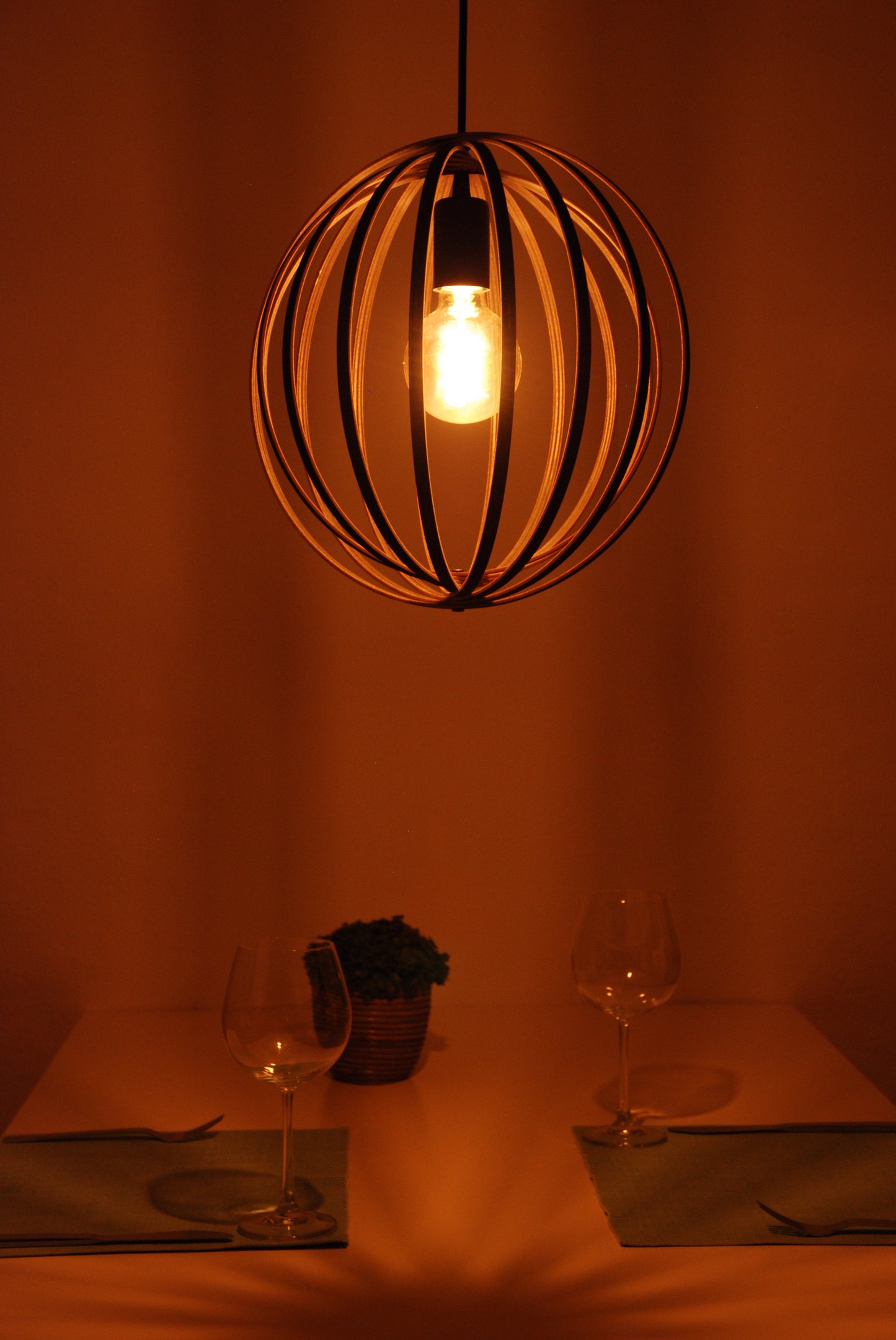 LUWALD NO.03 S Pendelleuchte aus Holz, schwarz, handgefertigt, kugelförmig, angeschaltet, Seitenansicht, Tisch Deko, warm