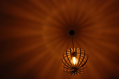 LUWALD NO.03 S Pendelleuchte aus Holz, schwarz, handgefertigt, kugelförmig, angeschaltet, schräg von unten, Schatten an Decke