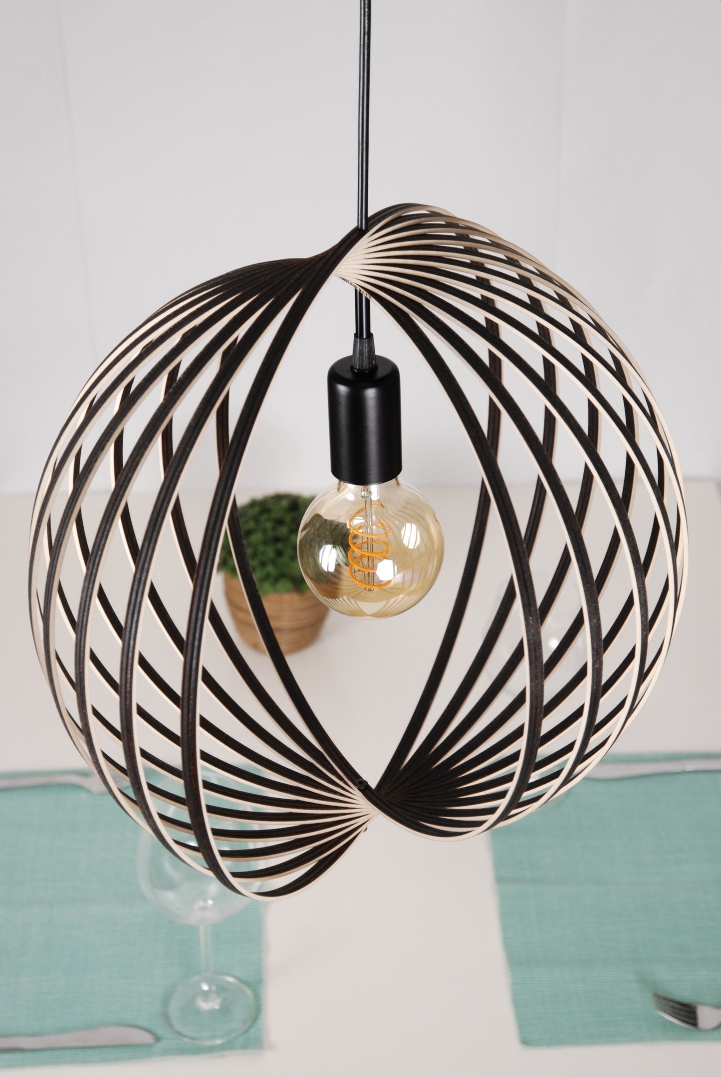 LUWALD NO.03 M Pendelleuchte aus Holz, schwarz, handgefertigt, kugelförmig, angeschaltet, schräg von oben, offene Form