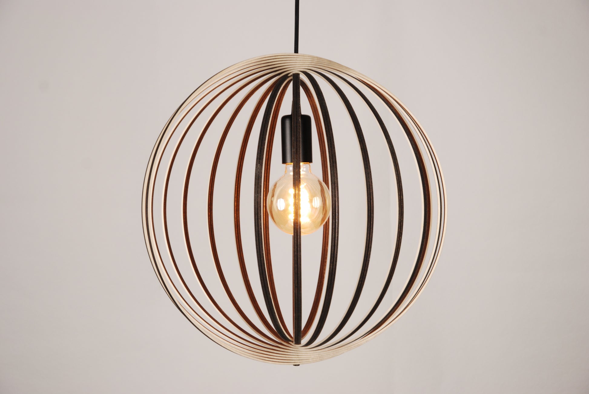 LUWALD NO.03 M Pendelleuchte aus Holz, schwarz, handgefertigt, kugelförmig, angeschaltet, Seitenansicht