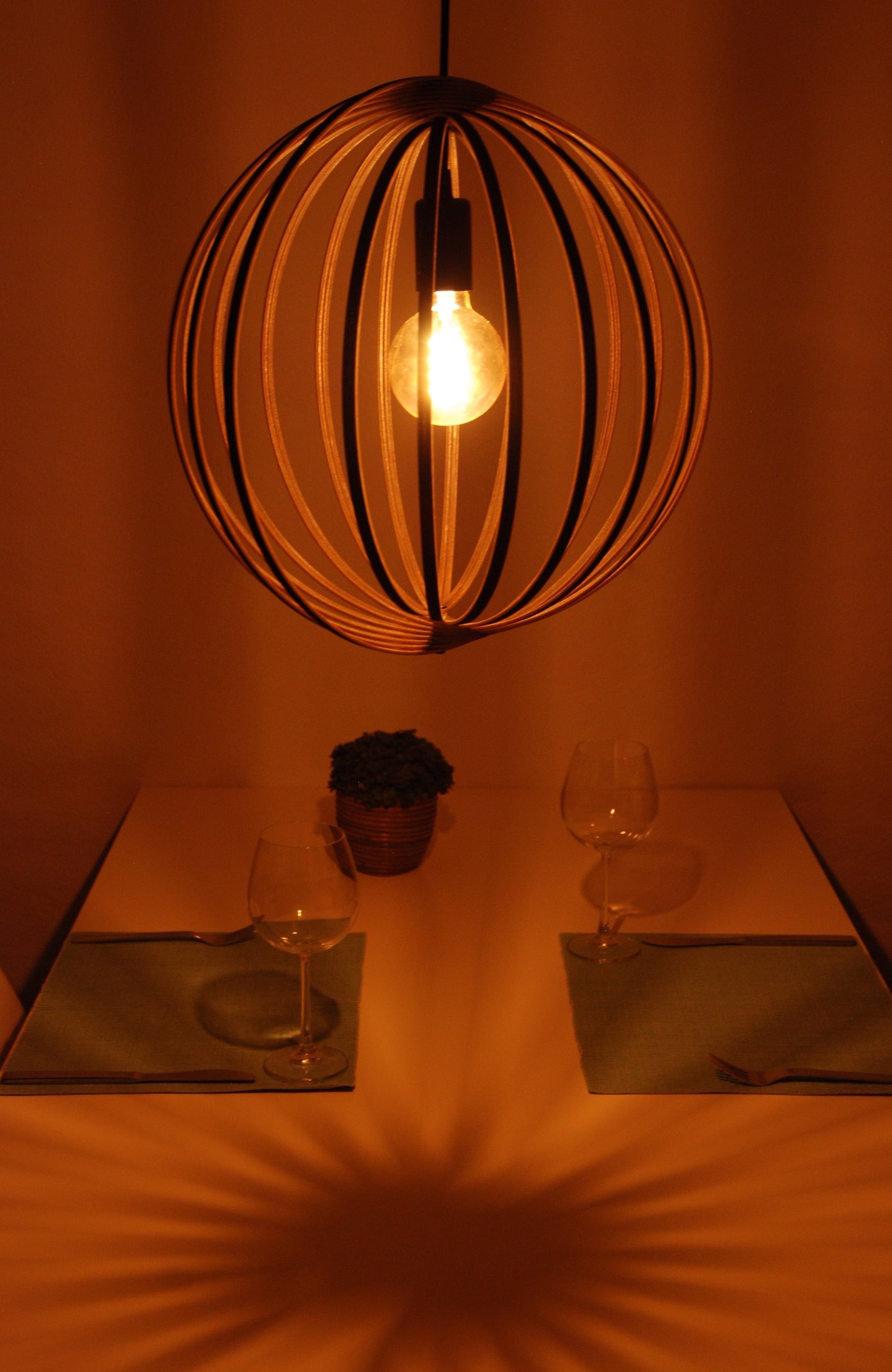 LUWALD NO.03 M Pendelleuchte aus Holz, schwarz, handgefertigt, kugelförmig, angeschaltet, Tisch mit Deko, gemütlich