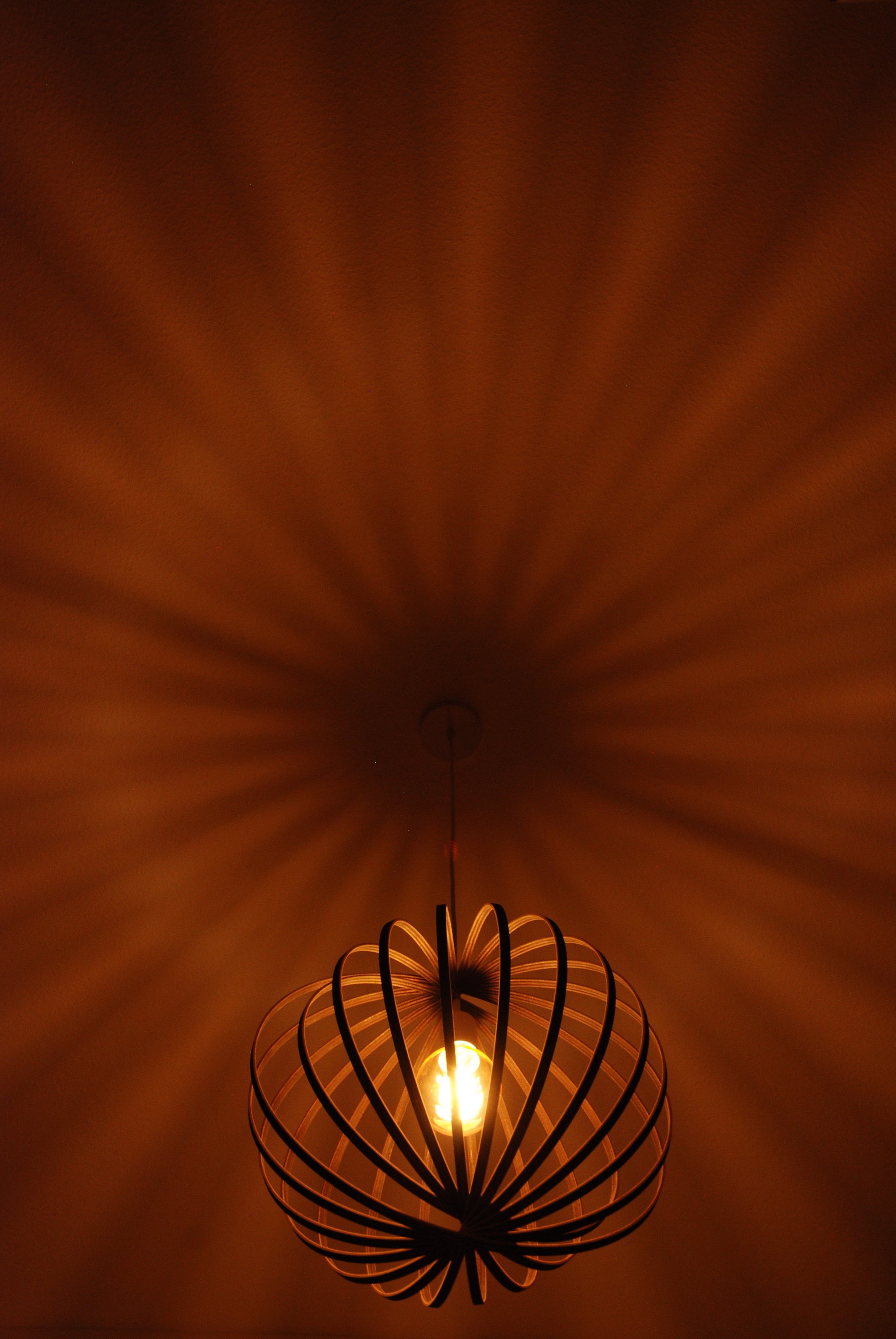 LUWALD NO.03 M Pendelleuchte aus Holz, weiß, handgefertigt, kugelförmig, angeschaltet, Schatten an Decke, warm