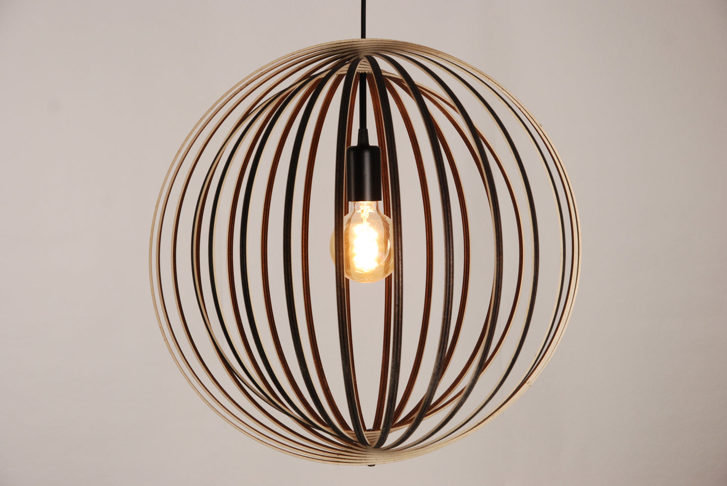 LUWALD NO.03 L Pendelleuchte aus Holz, schwarz, handgefertigt, kugelförmig, angeschaltet, Seitenansicht