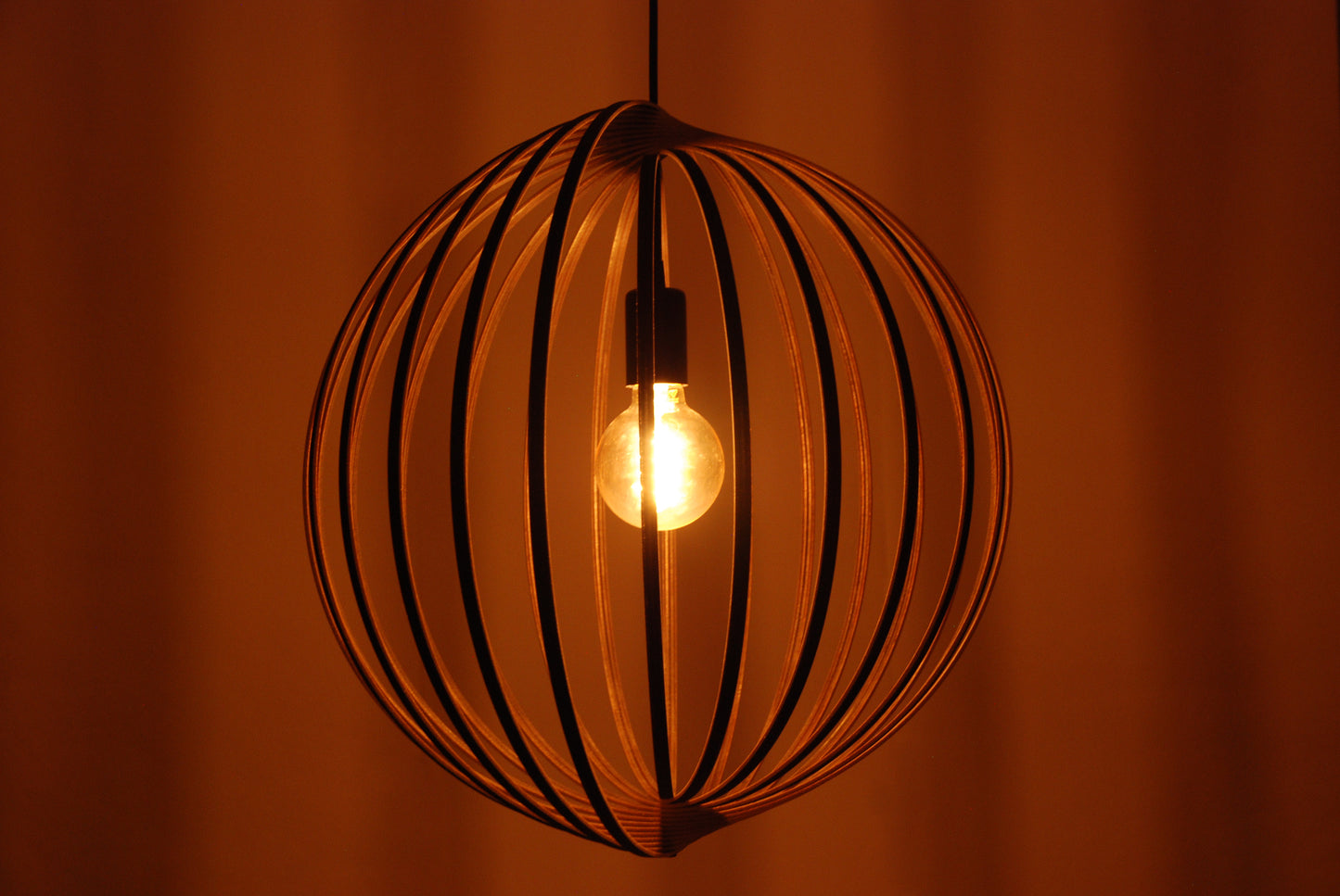 LUWALD NO.03 L Pendelleuchte aus Holz, schwarz, handgefertigt, kugelförmig, angeschaltet, Seitenansicht, warm