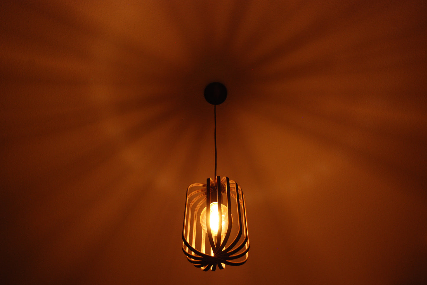 LUWALD NO.04 S Pendelleuchte aus Holz, schwarz, handgefertigt, zylinderförmig, angeschaltet, Ringe, Atmosphäre, Hängelampe, warm, Schatten an der Decke