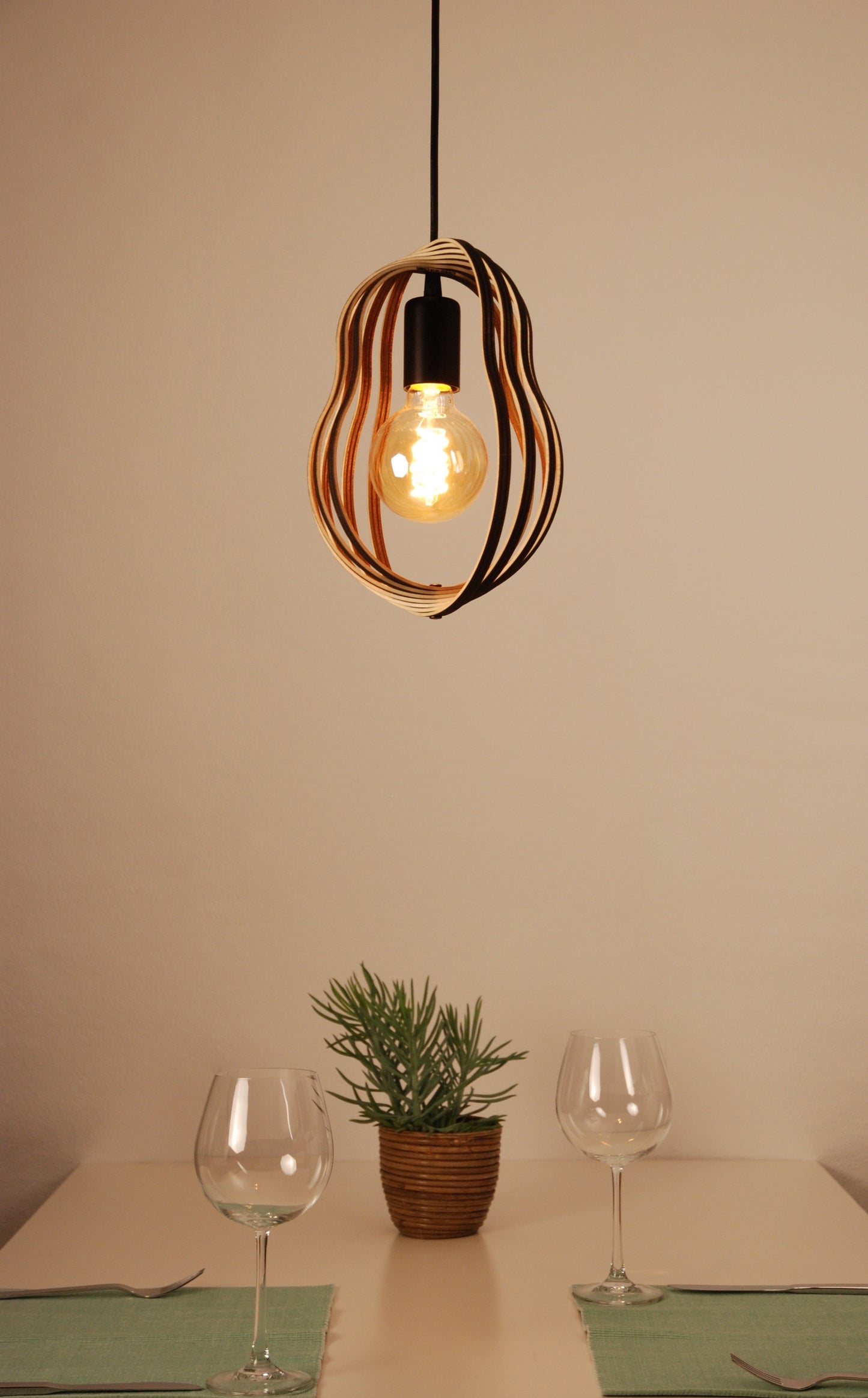 LUWALD NO.02 S, Pendelleuchte aus Holz, schwarz, handgefertigt, birnenförmig, angeschaltet, offene Form, Tisch, Deko