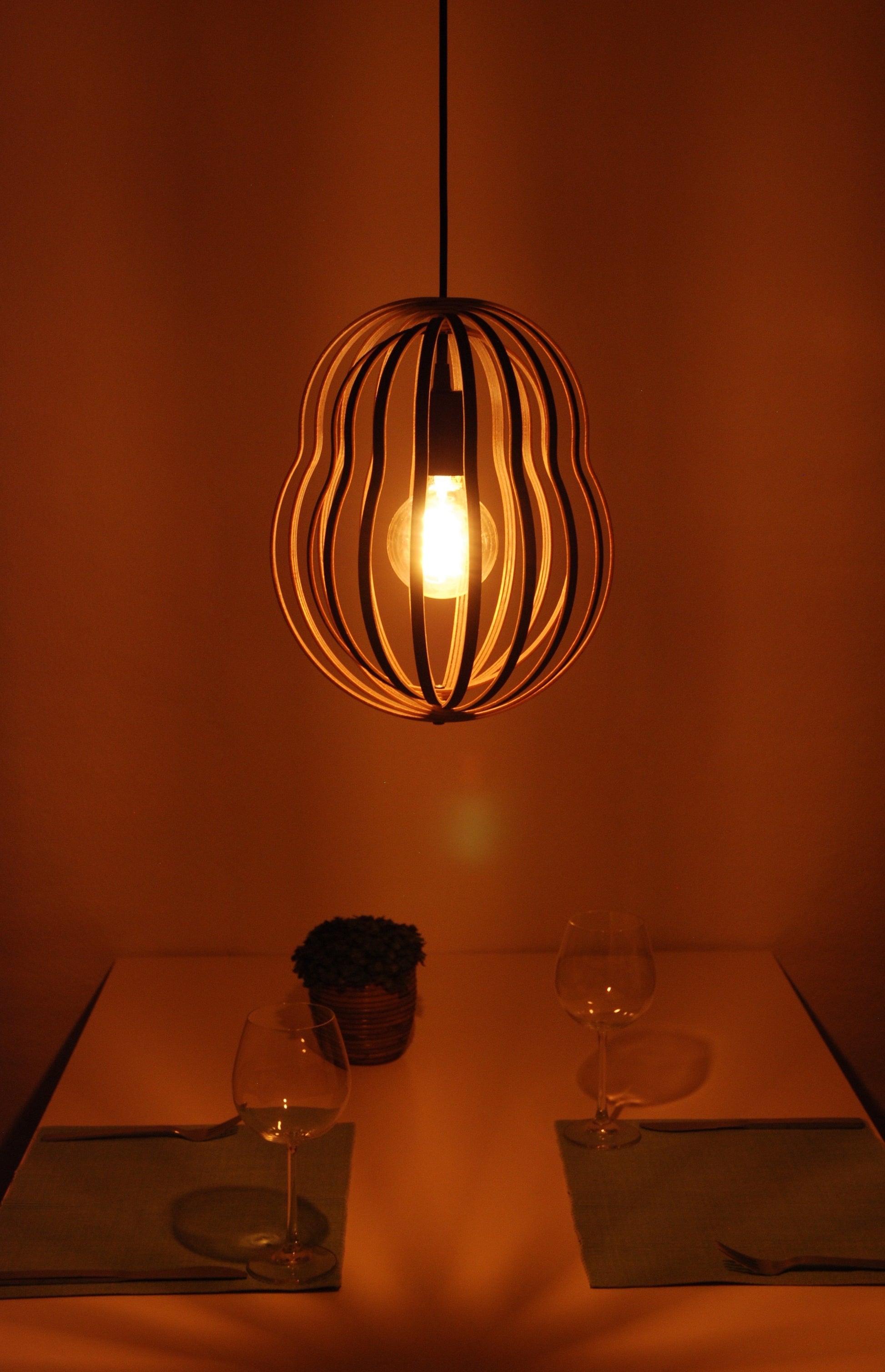 LUWALD NO.02 M Pendelleuchte aus Holz, schwarz, handgefertigt, birnenförmig, angeschaltet, Tisch, Deko