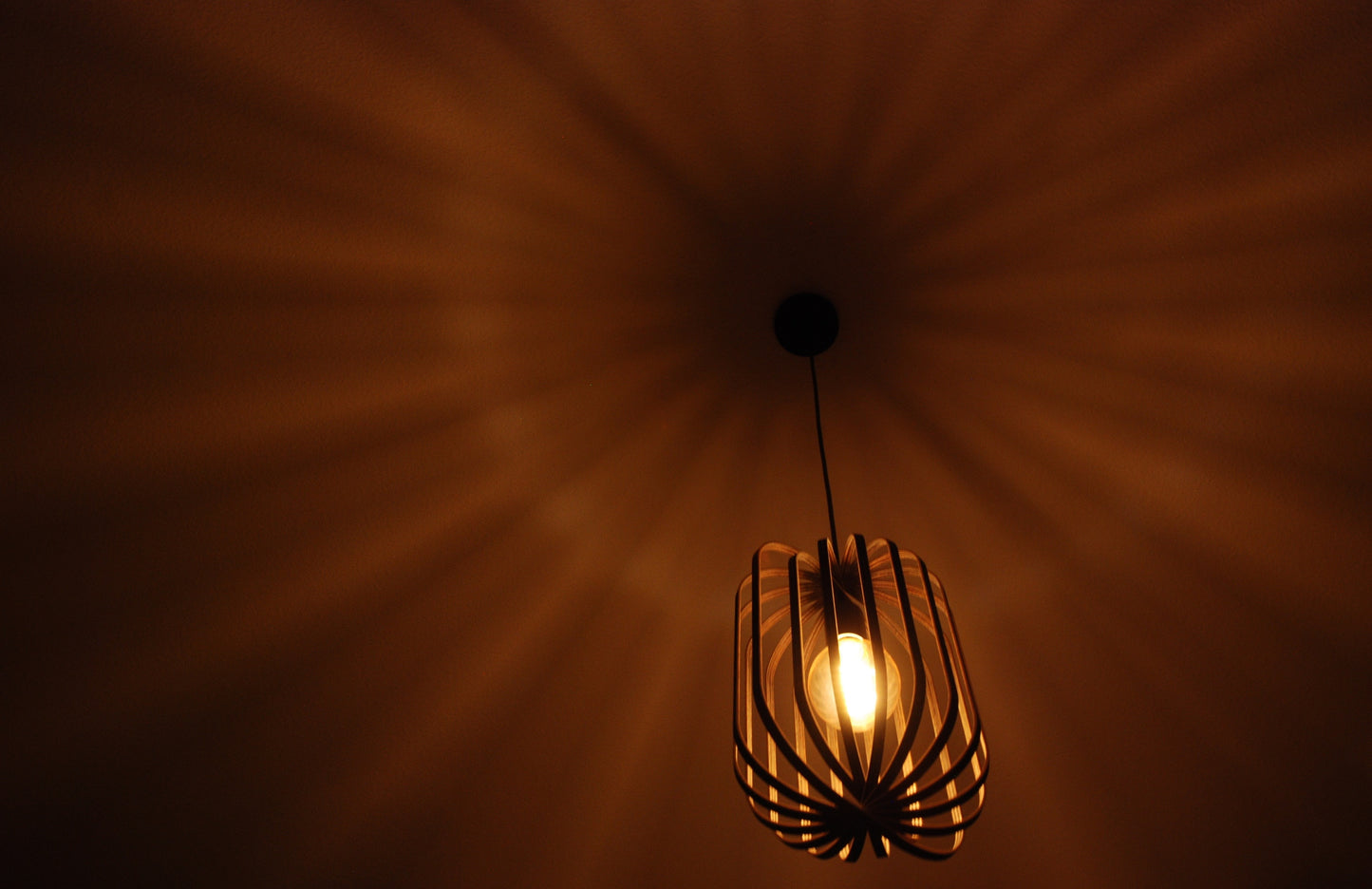 LUWALD NO.04 M Pendelleuchte aus Holz, schwarz, handgefertigt, zylinderförmig, angeschaltet, Ringe, Atmosphäre, Hängelampe,  Schatten an Decke