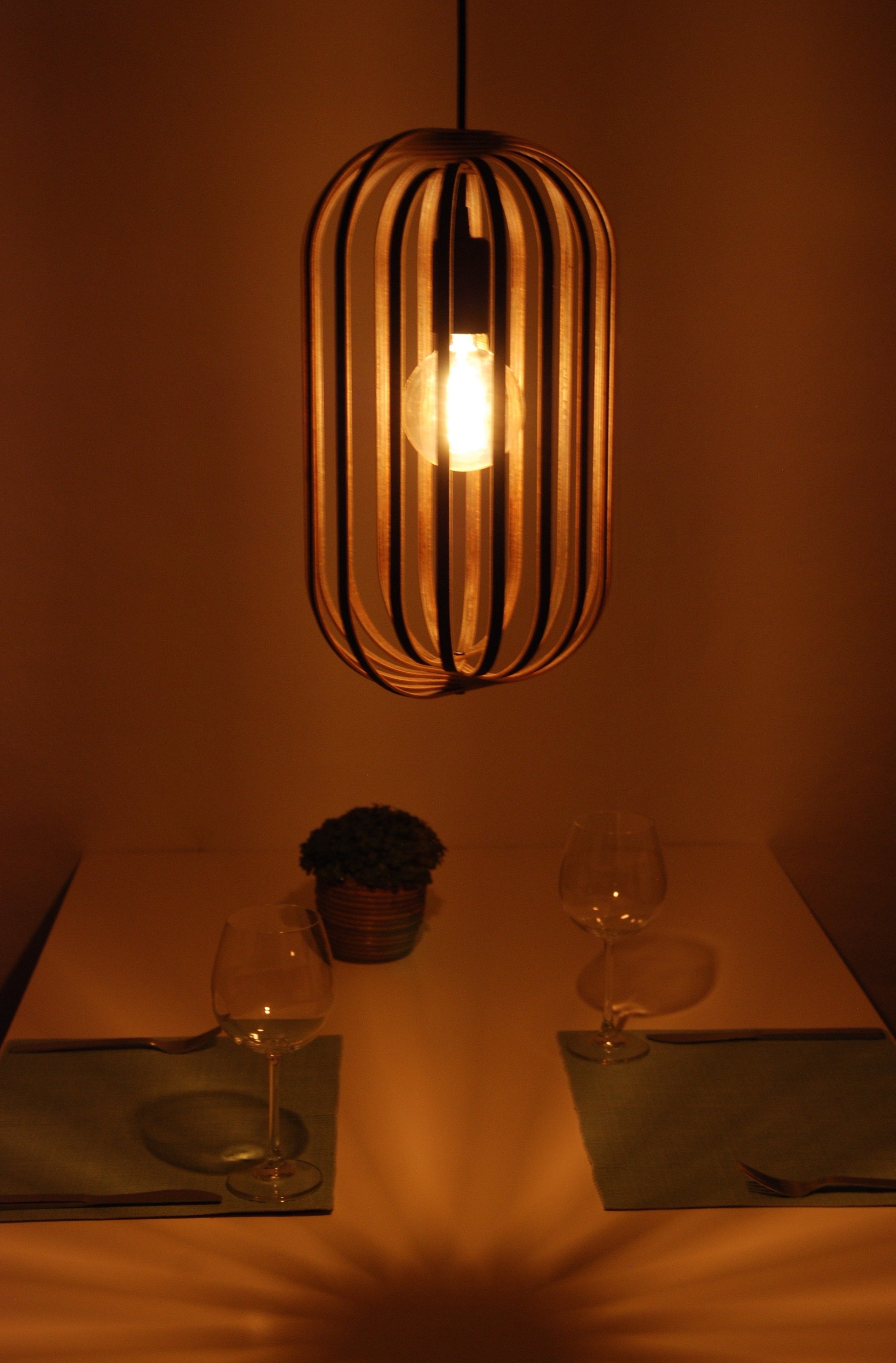 LUWALD NO.04 M Pendelleuchte aus Holz, schwarz, handgefertigt, zylinderförmig, angeschaltet, Ringe, Atmosphäre, Hängelampe,  Seitenansicht, Deko Tisch, warm