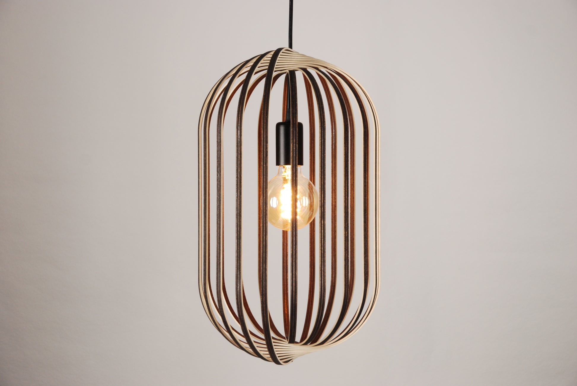 LUWALD NO.04 L Pendelleuchte aus Holz, schwarz, handgefertigt, zylinderförmig, angeschaltet, Ringe, Atmosphäre, Hängelampe, Seitenansicht